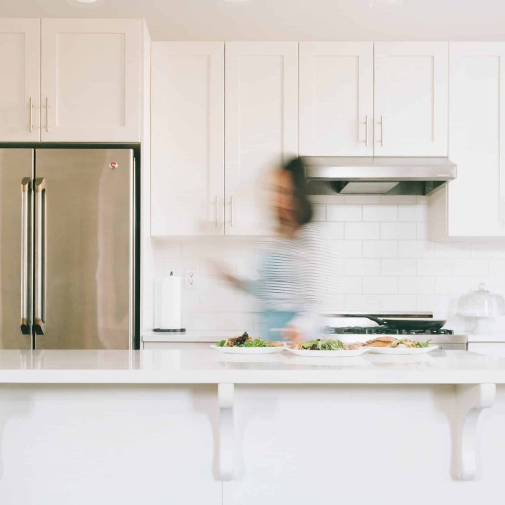 a-bright-white-kitchen-with-a-woman-walking-throug-2024-10-18-04-54-21-utc