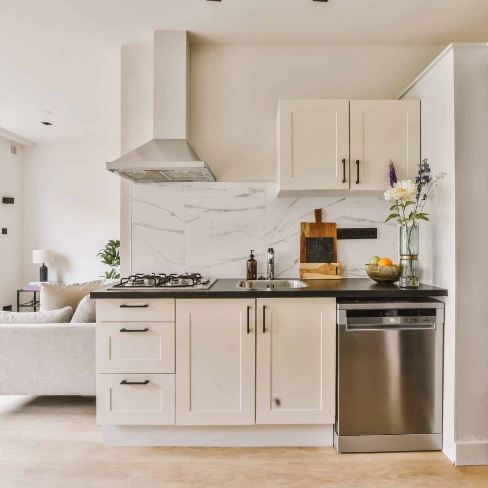 a modern kitchen with marble counter tops and white cabinetry in the room is well lit by the large window