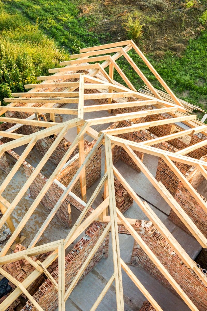 Aerial view of unfinished brick house with wooden roof structure Aerial view of unfinished brick house with wooden roof structure under construction.