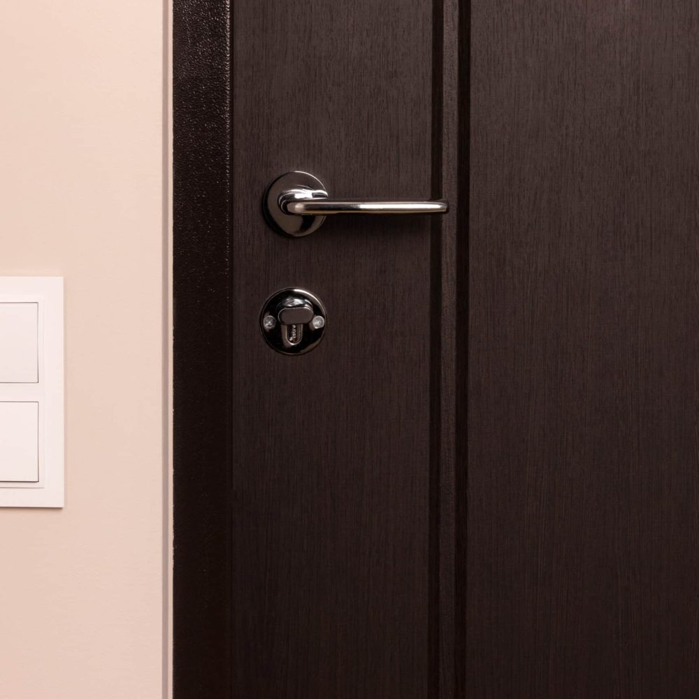 White electrical switch on beige wall next to the wooden door in modern apartment